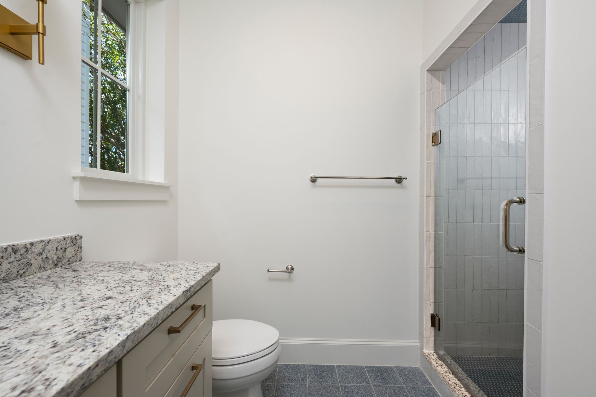 A bathroom with a toilet , sink , shower and window.