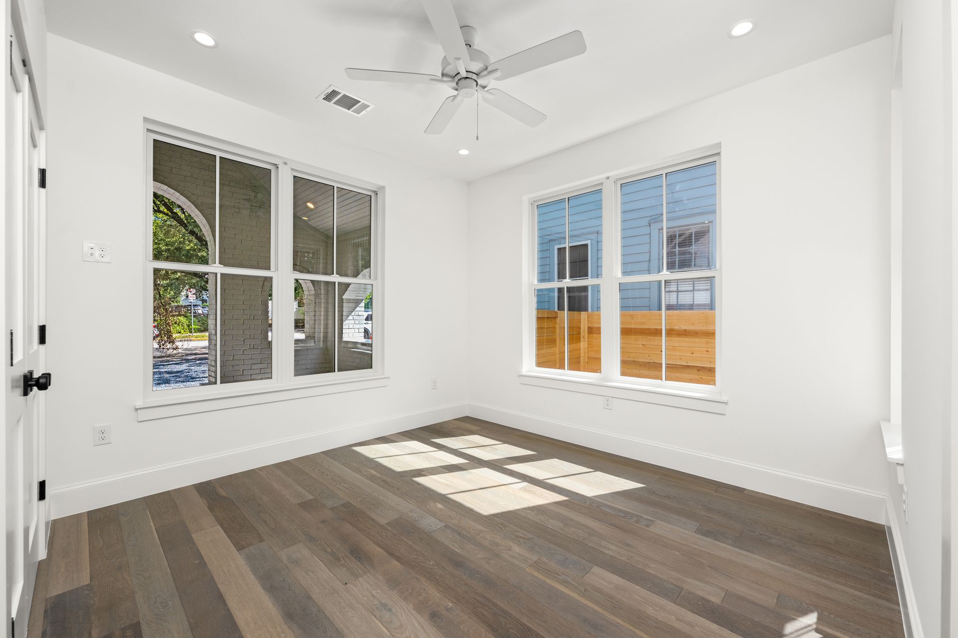 An empty room with hardwood floors and a ceiling fan.