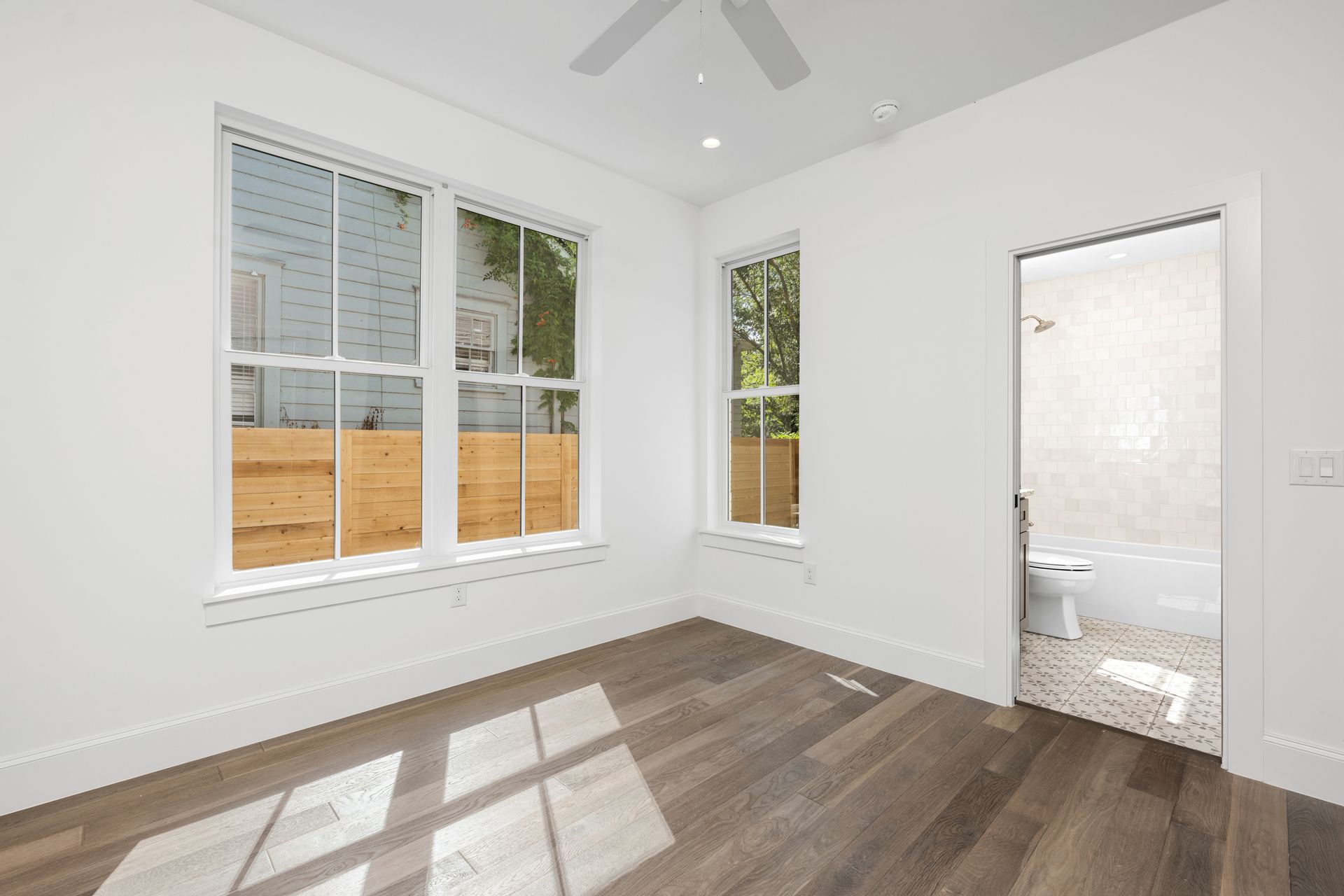 An empty bedroom with hardwood floors and a ceiling fan.