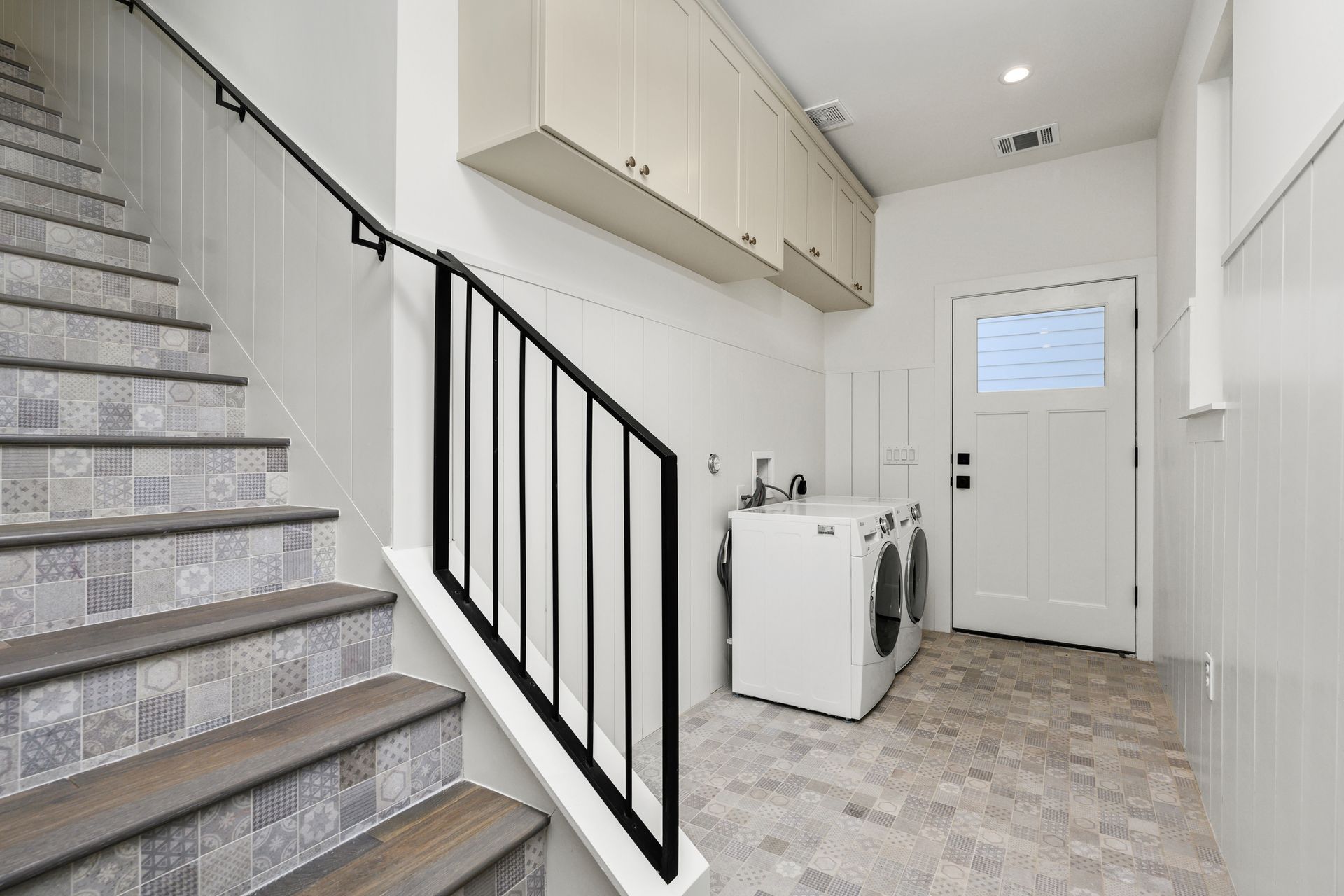 A laundry room with stairs leading up to it and a washer and dryer.