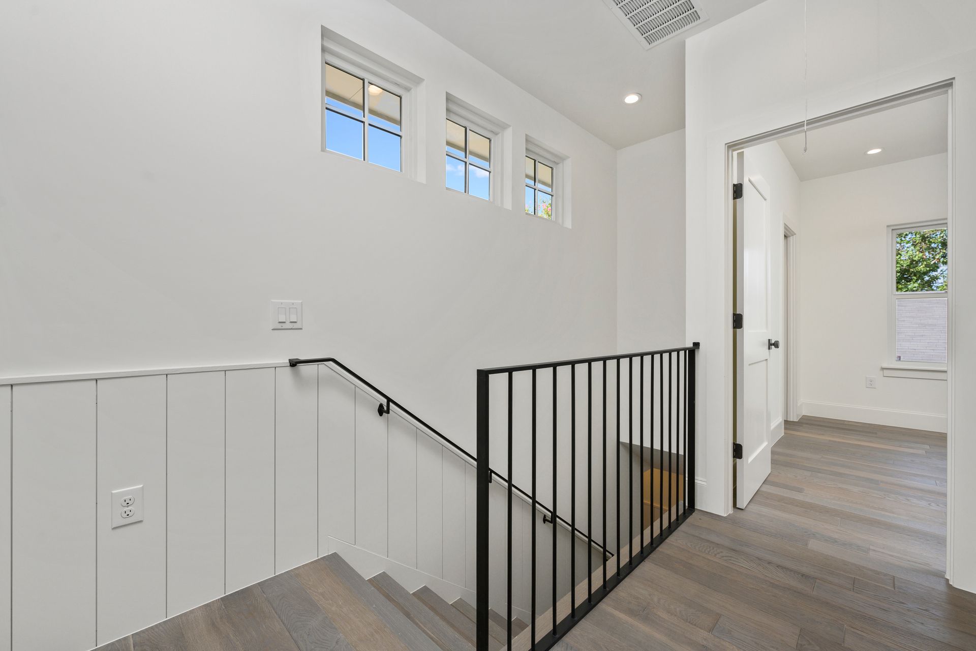 A staircase with a black railing and white walls in a house.