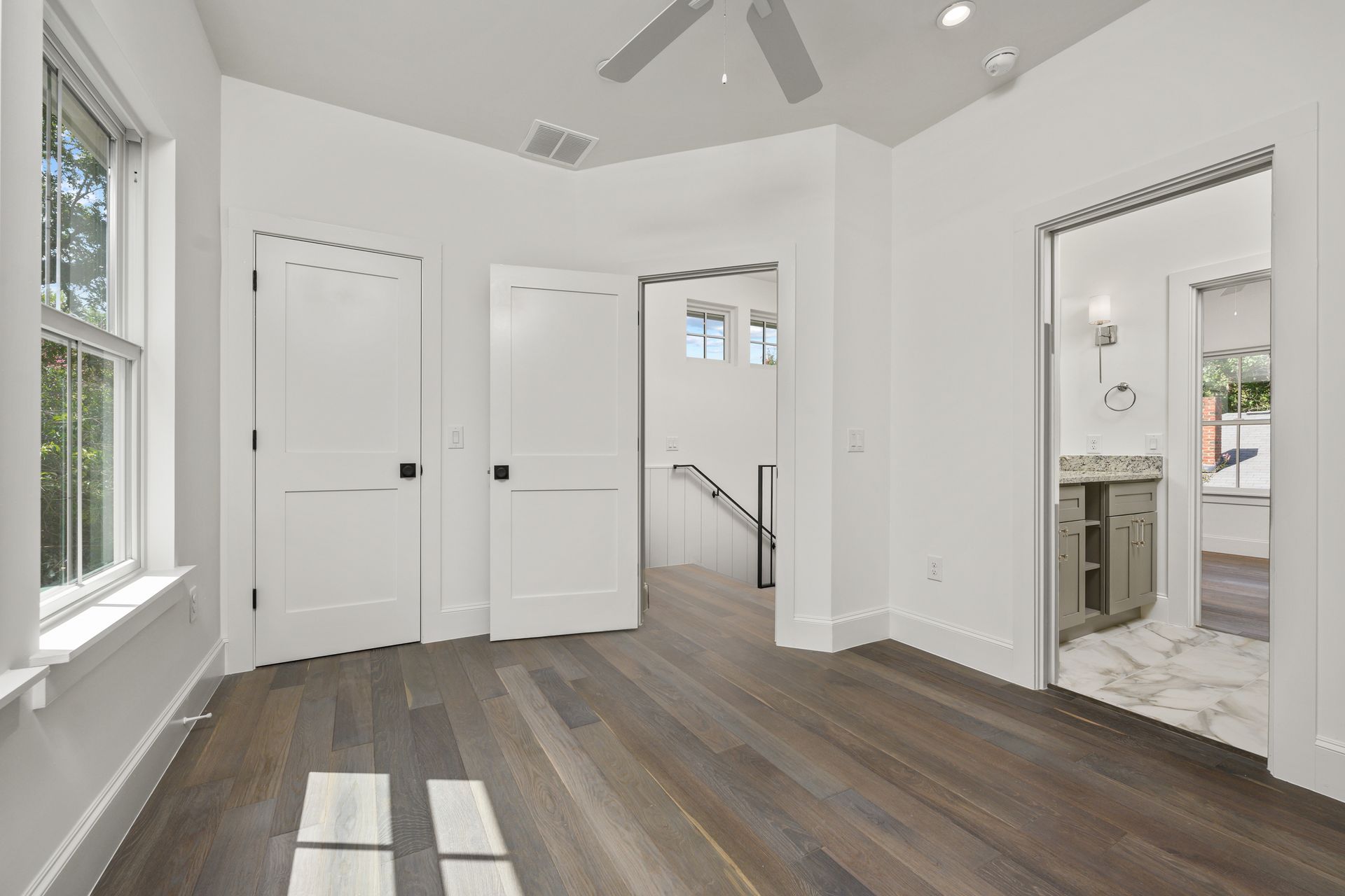 An empty room with hardwood floors and a ceiling fan.