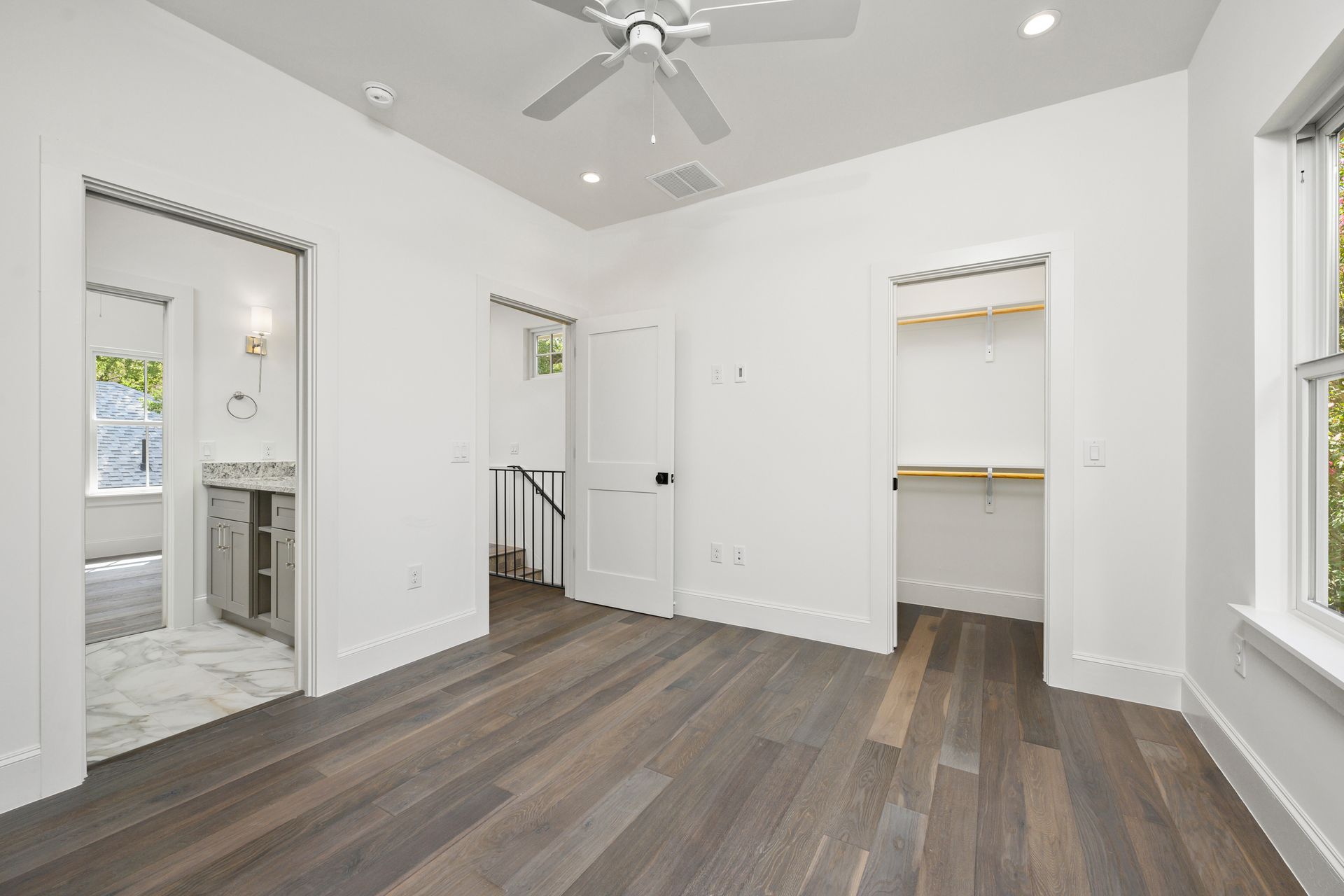An empty bedroom with hardwood floors and a ceiling fan.