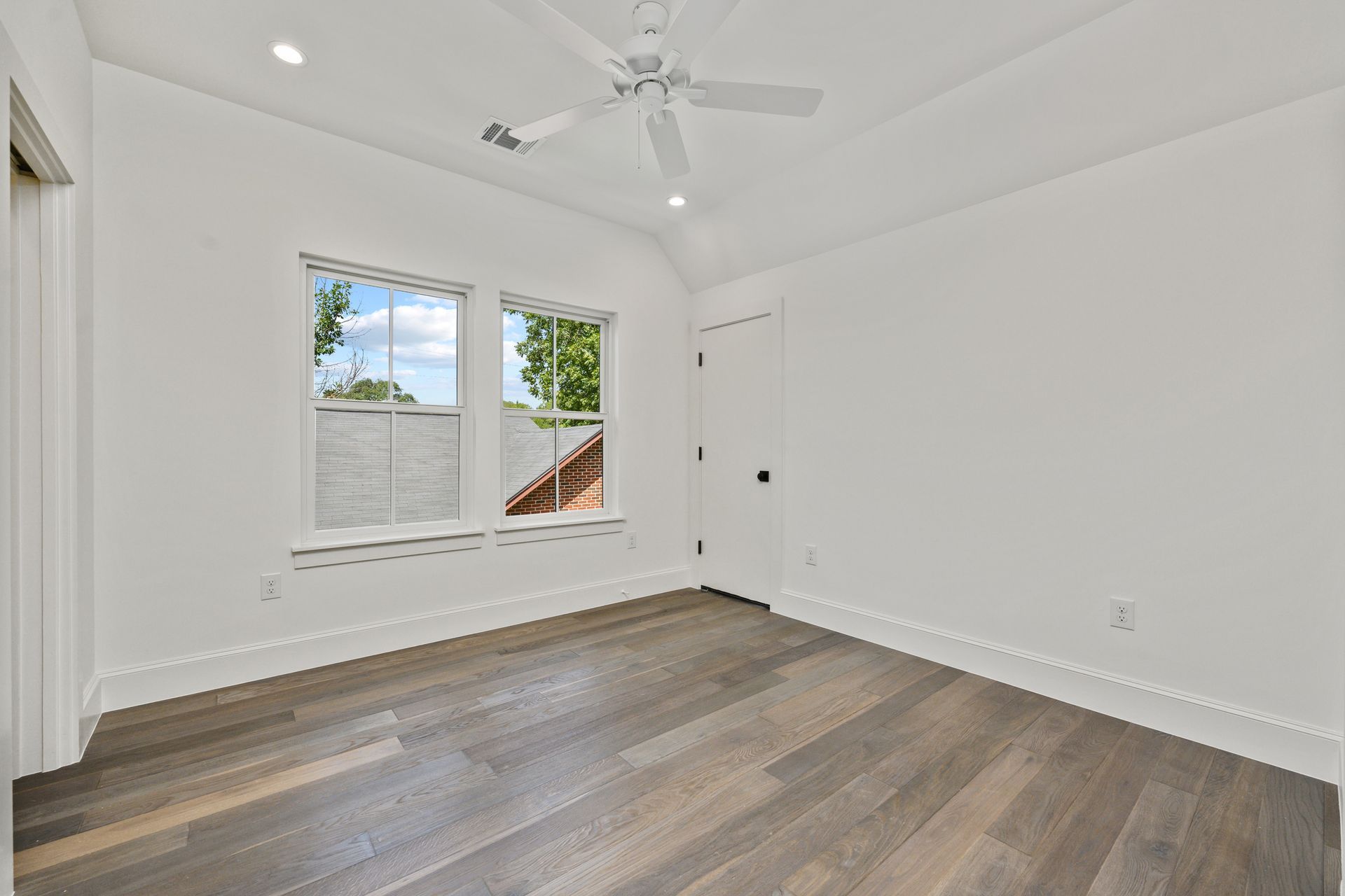 An empty bedroom with hardwood floors and a ceiling fan.