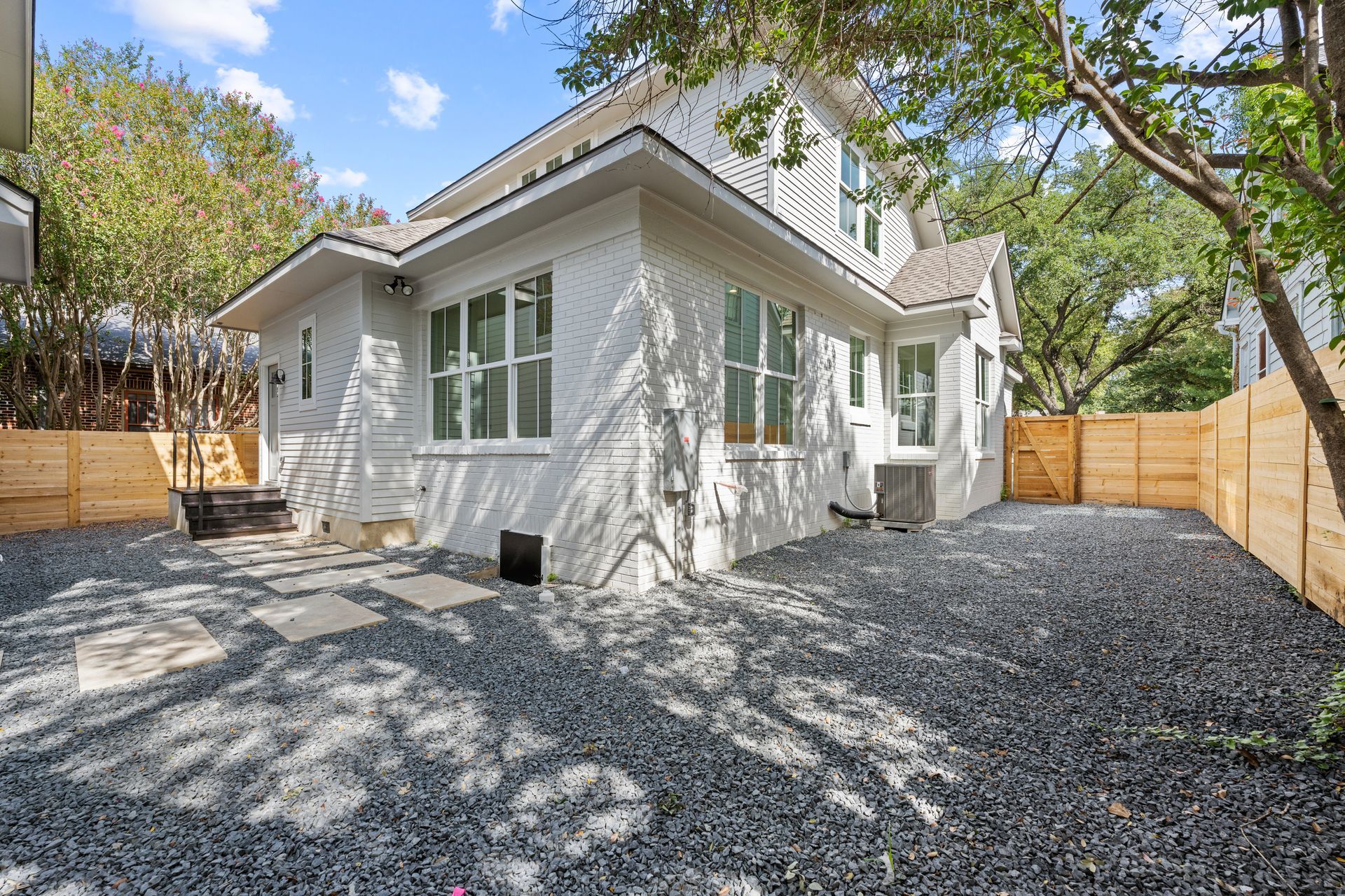 A white house with a gravel driveway in front of it.