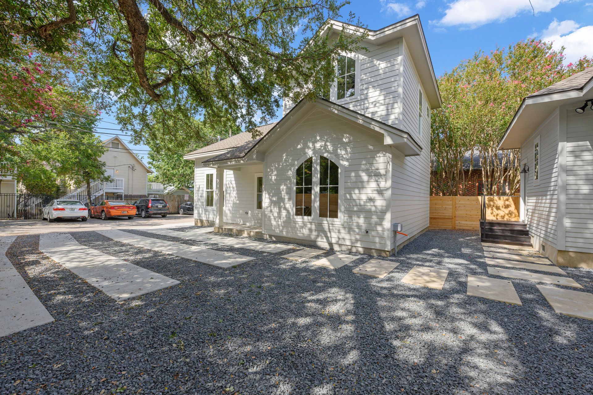 A white house with a gravel driveway in front of it.