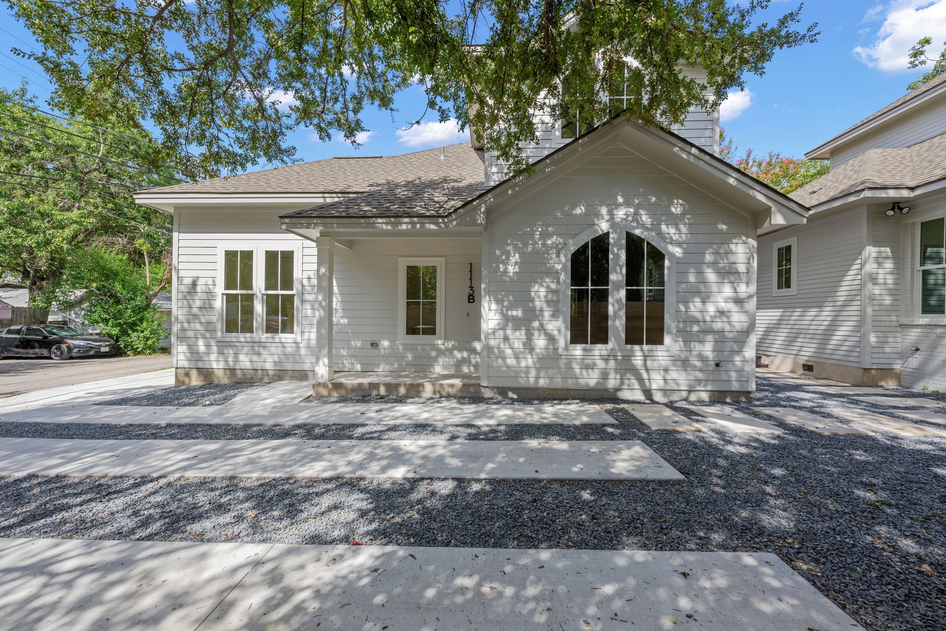 A white house with a gravel driveway in front of it.
