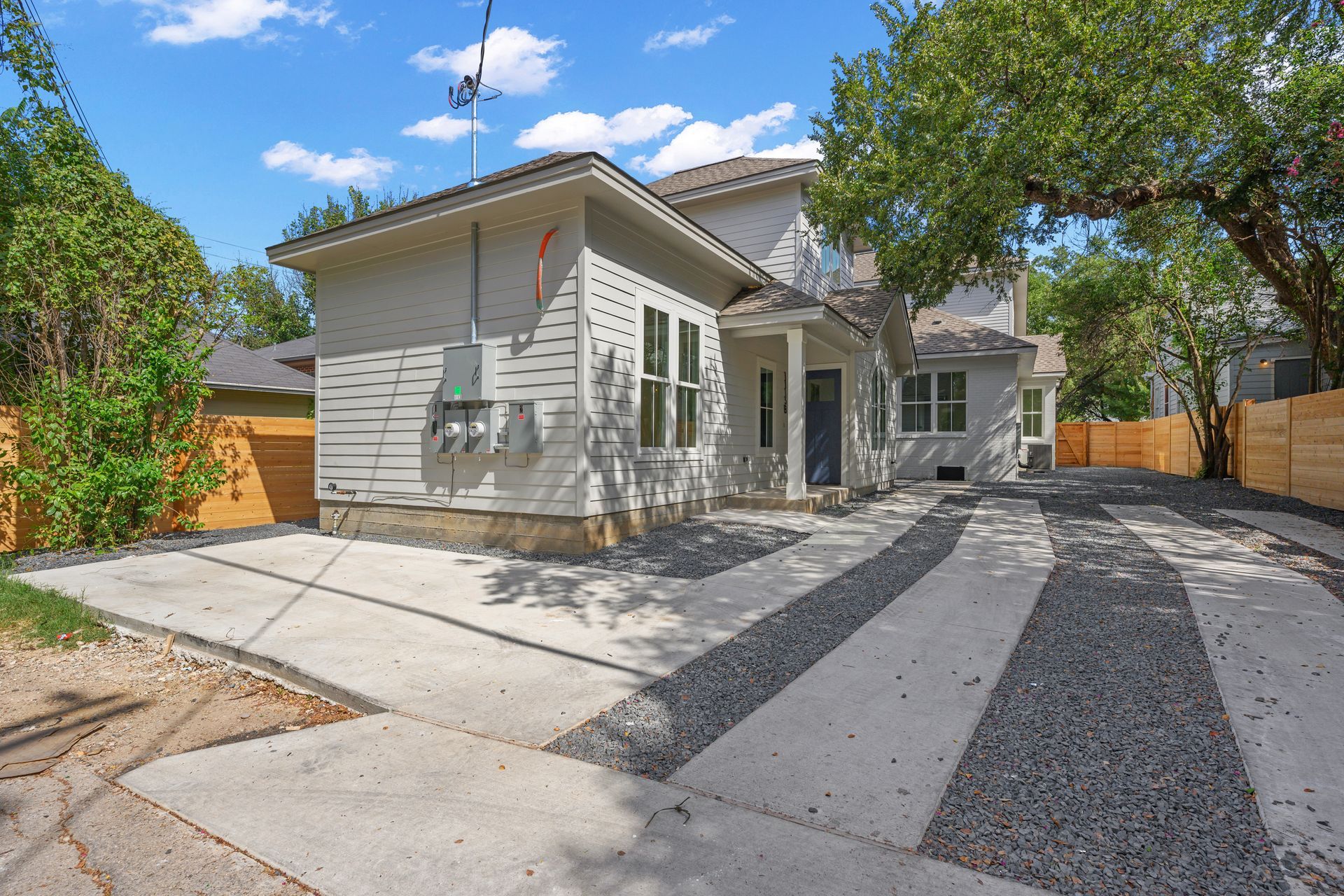 A white house with a gravel driveway in front of it