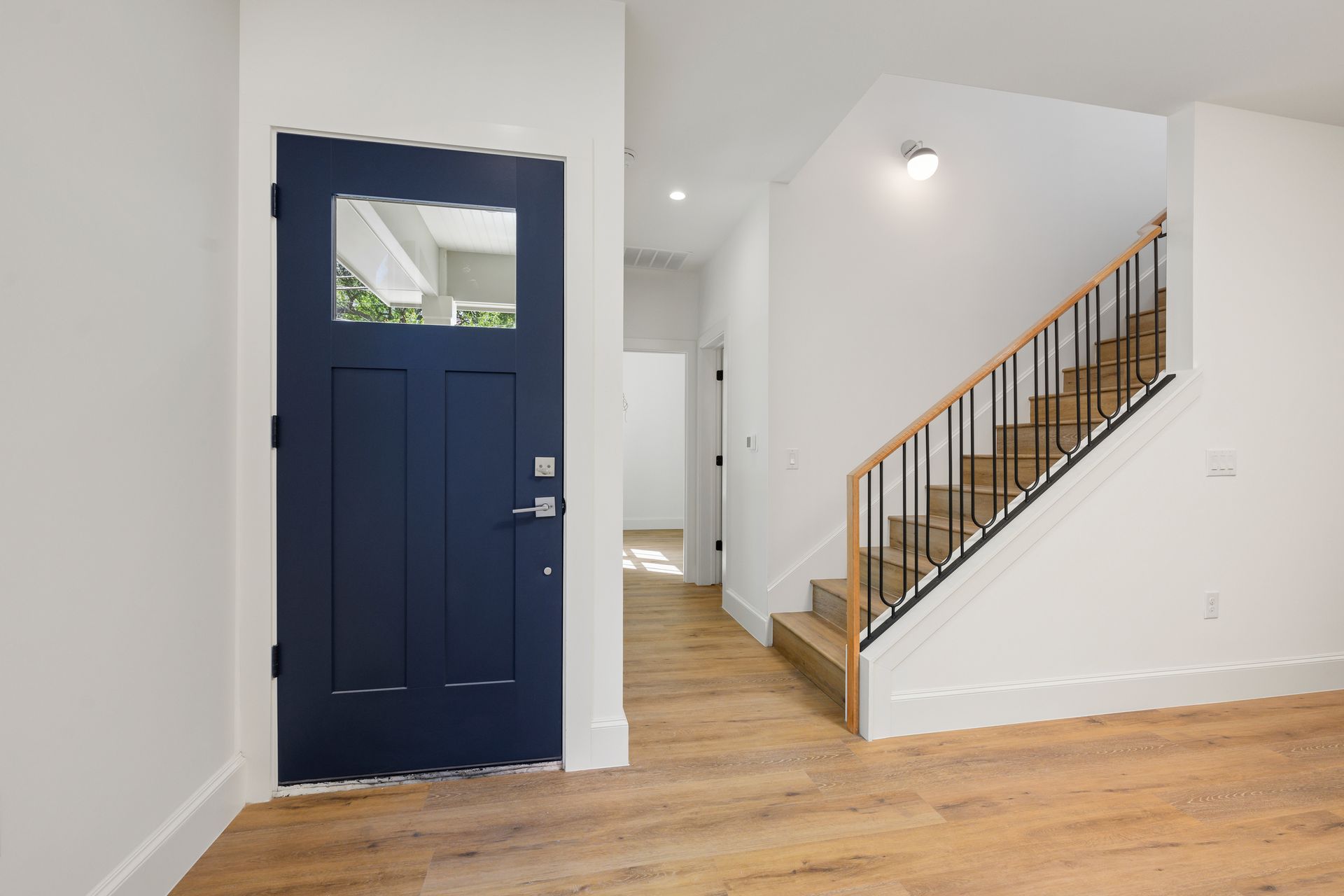 An empty room with a blue door and stairs.
