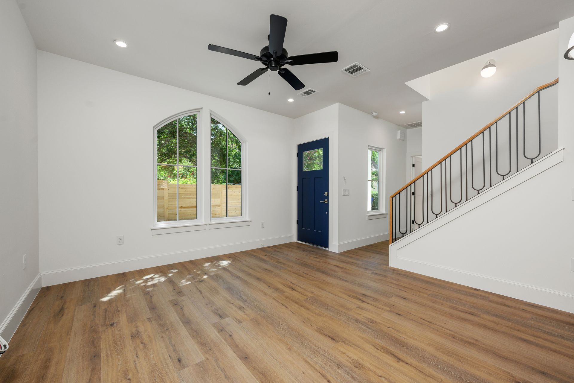 An empty living room with hardwood floors and a ceiling fan.