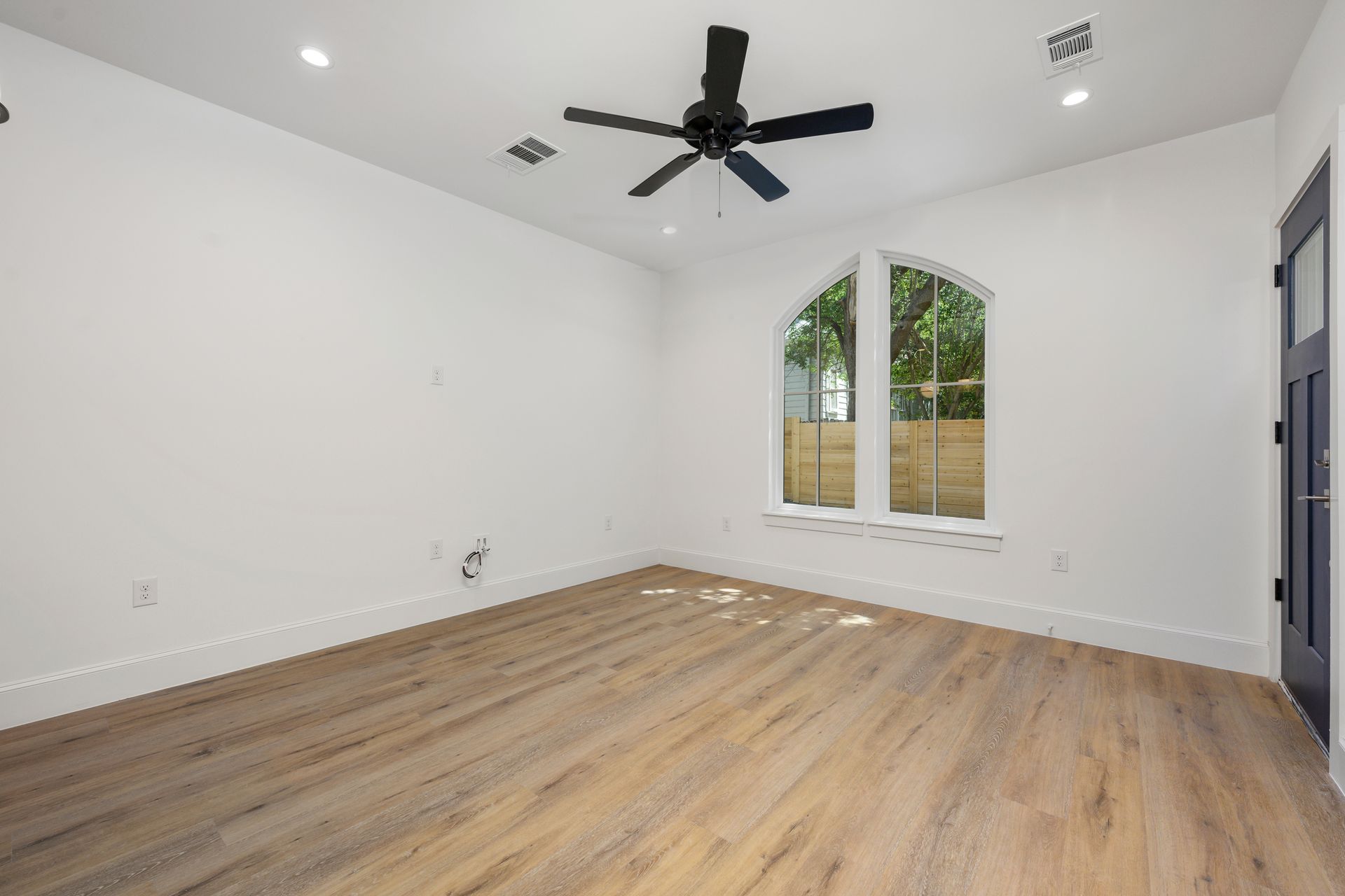 An empty room with hardwood floors and a ceiling fan.