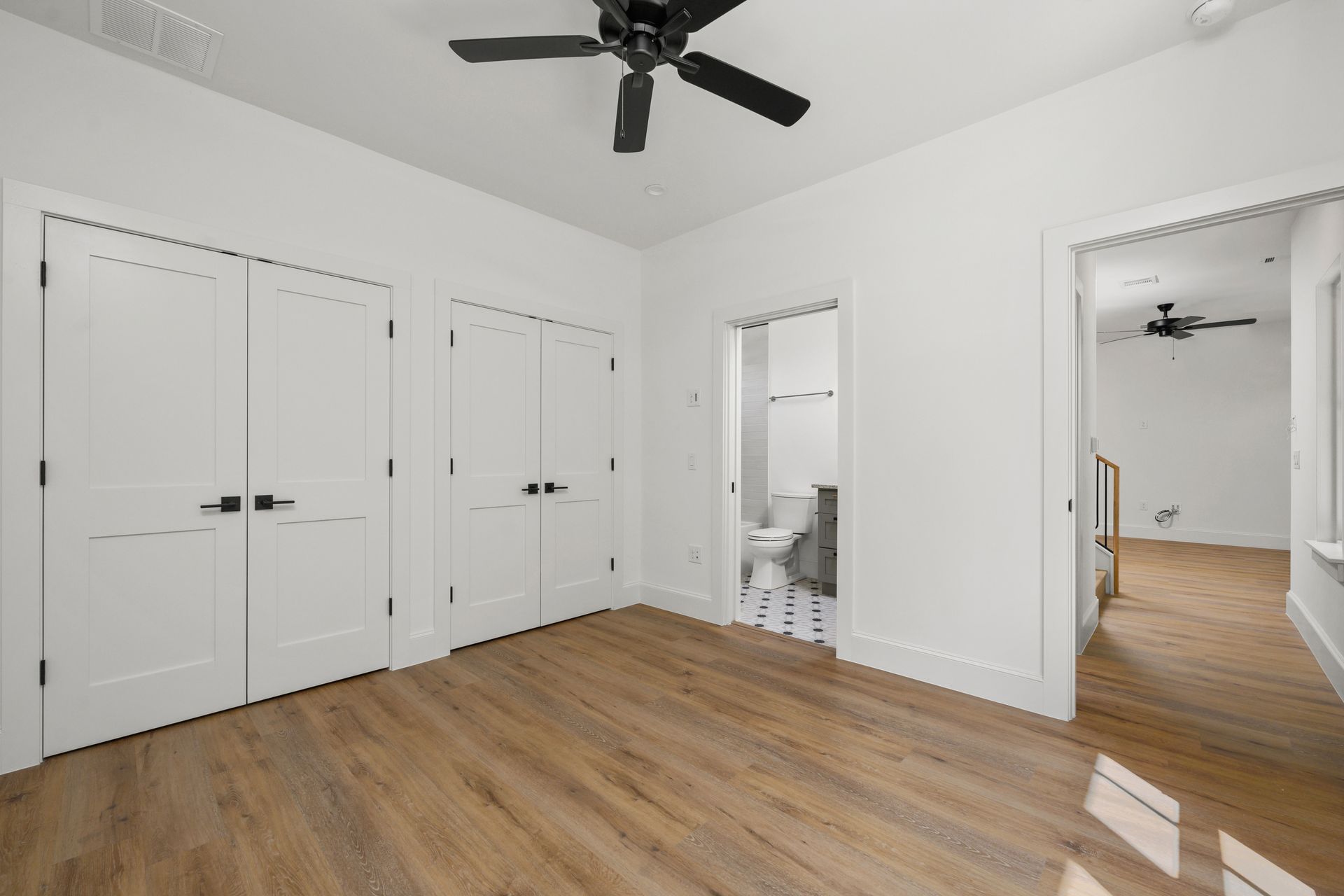An empty room with hardwood floors and a ceiling fan.