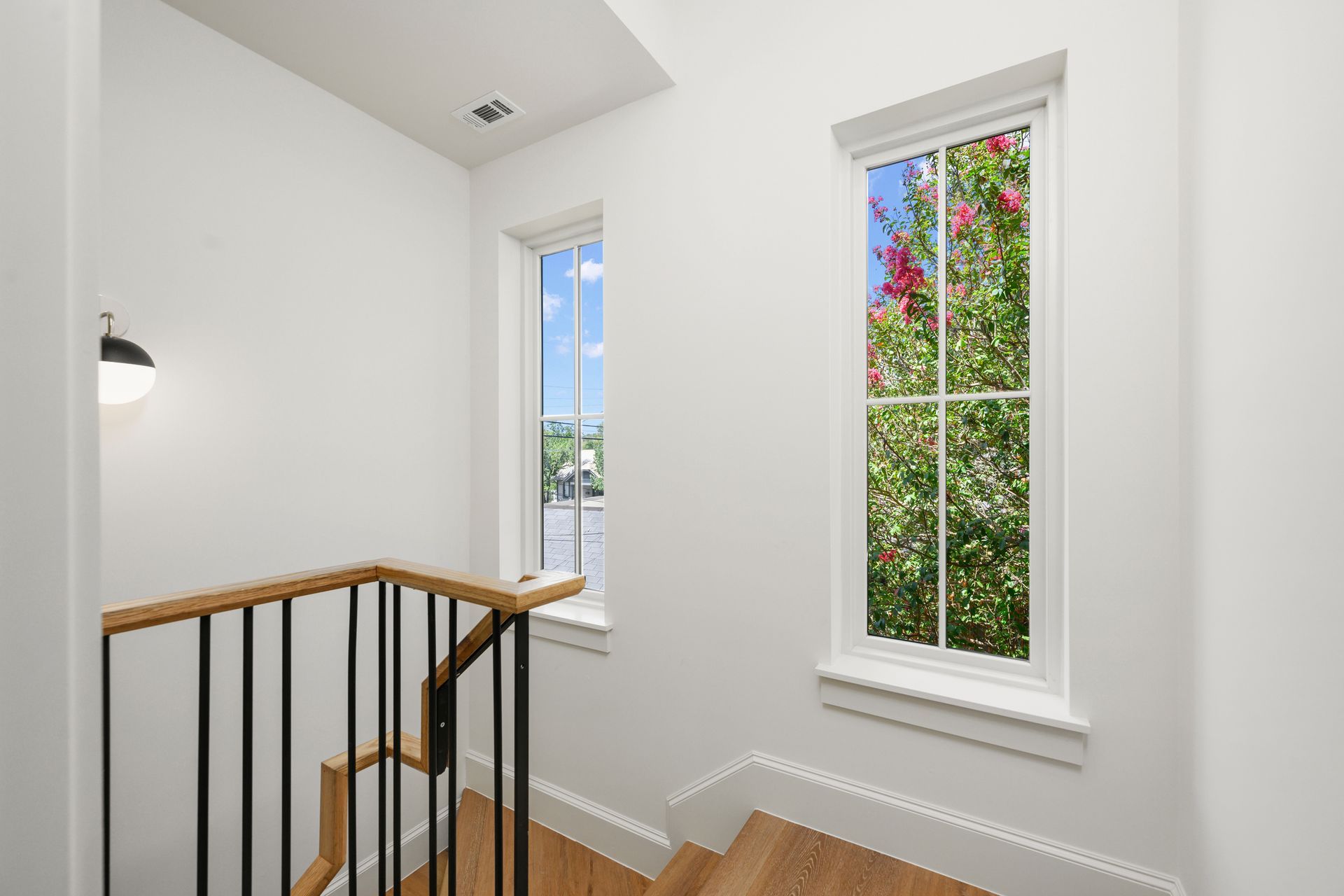 A staircase with a railing and a window on the second floor of a house.