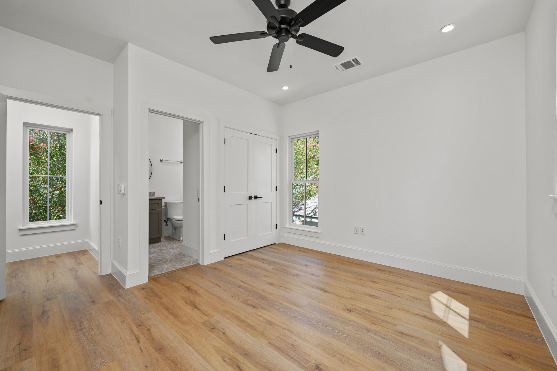 An empty bedroom with hardwood floors and a ceiling fan.