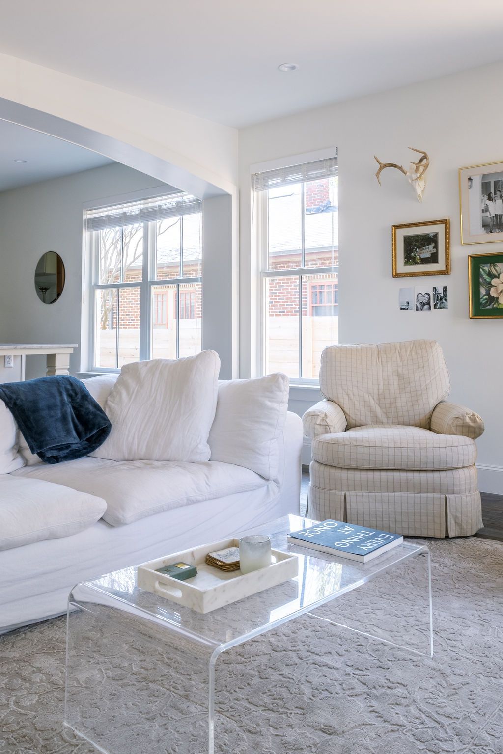 A living room with a white couch , chair , and clear coffee table.