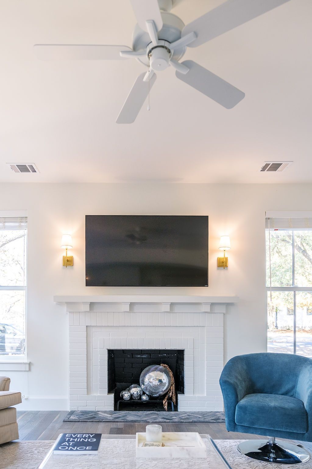 A living room with a fireplace , television and ceiling fan.