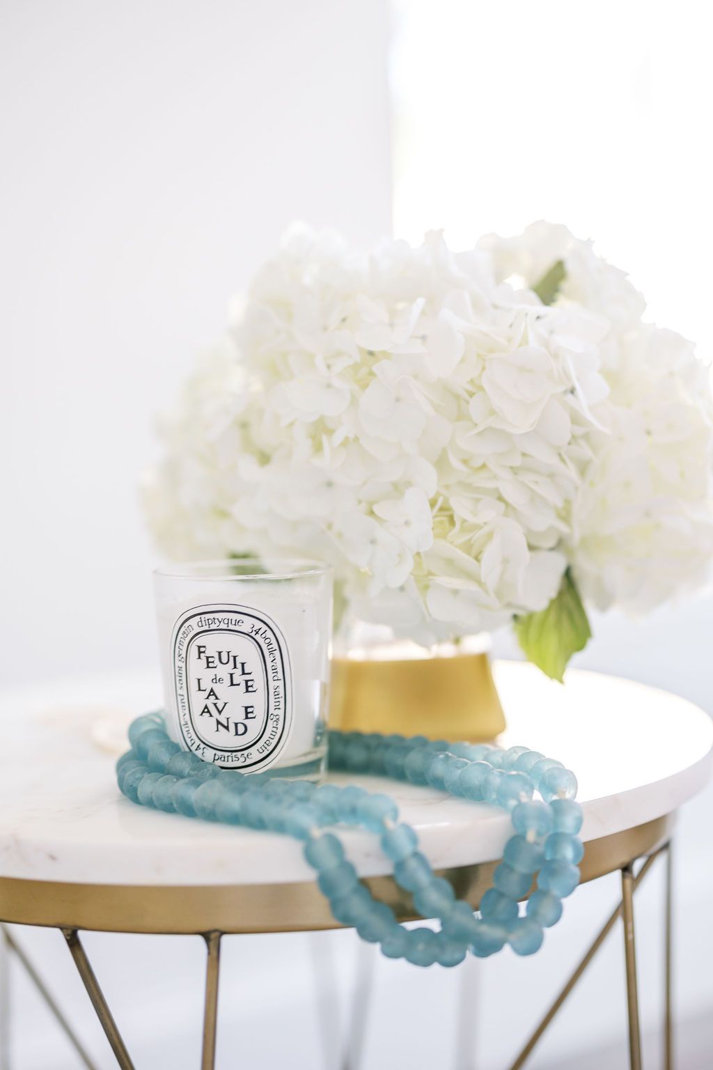 A candle is sitting on a table next to a vase of white flowers.