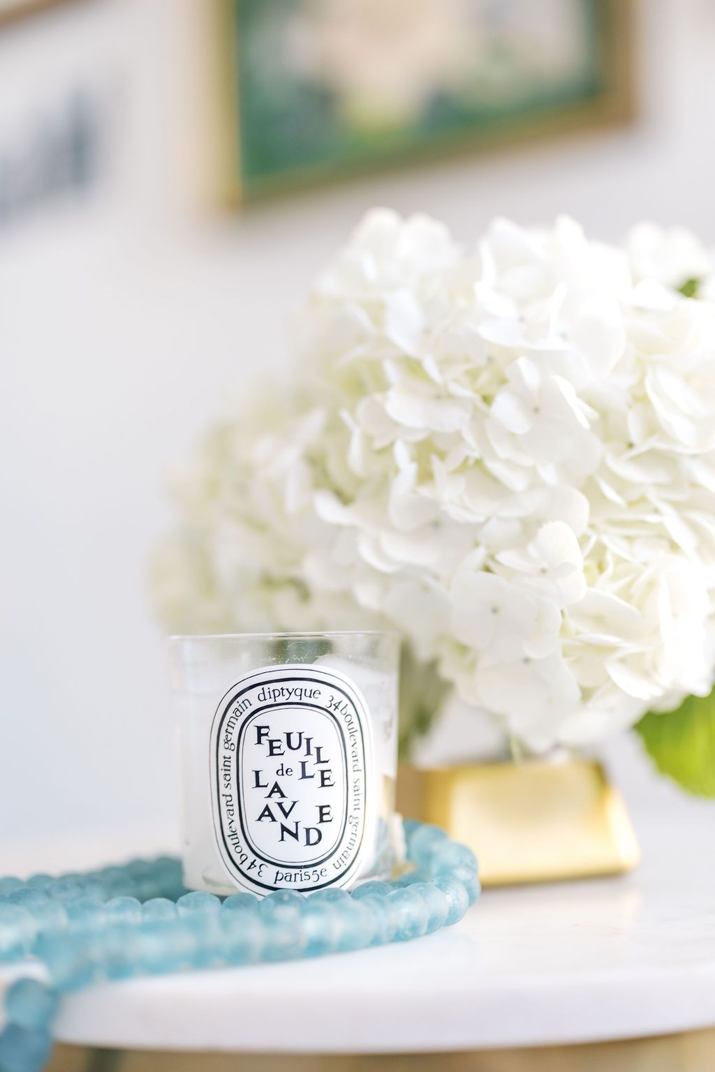 A candle is sitting on a table next to a vase of white flowers.