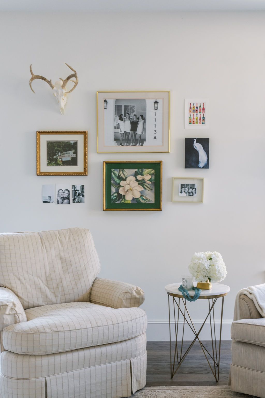 A living room with a chair , two chairs , a table and a deer head on the wall.
