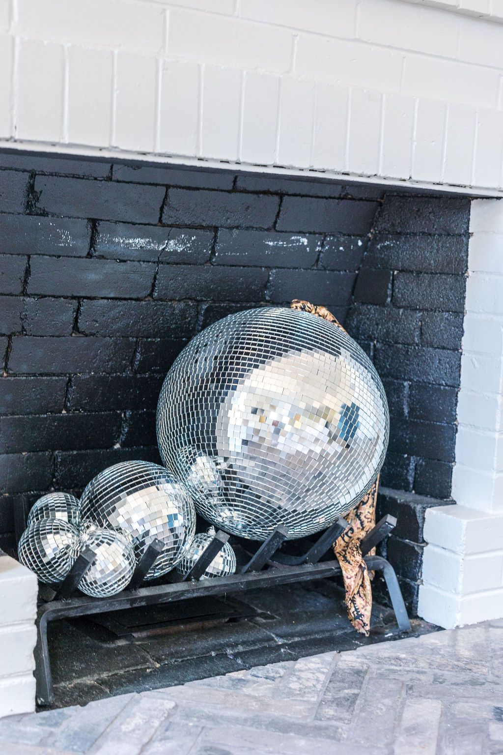 A bunch of disco balls are sitting in a fireplace.