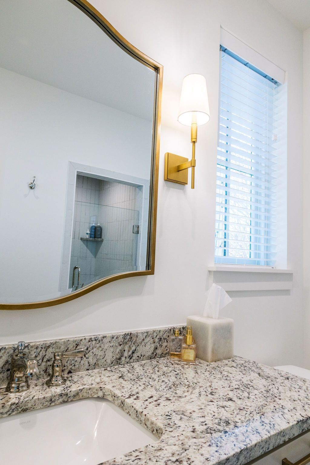 A bathroom with a sink , mirror and window.