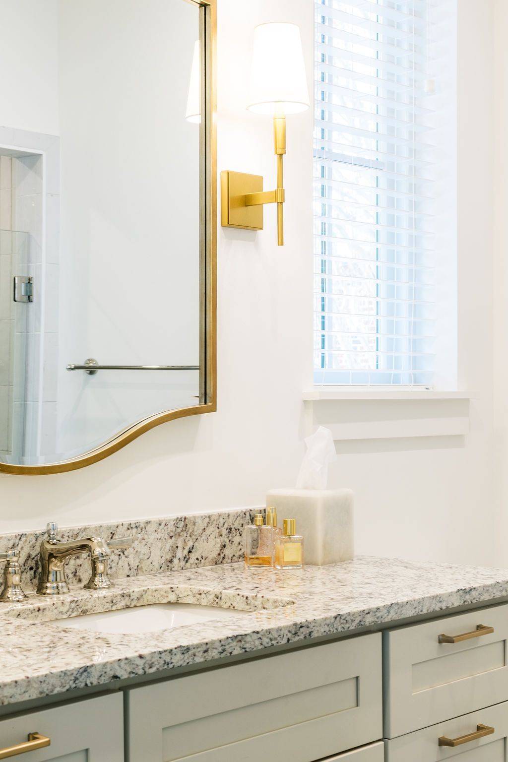 A bathroom with a sink , mirror and window.