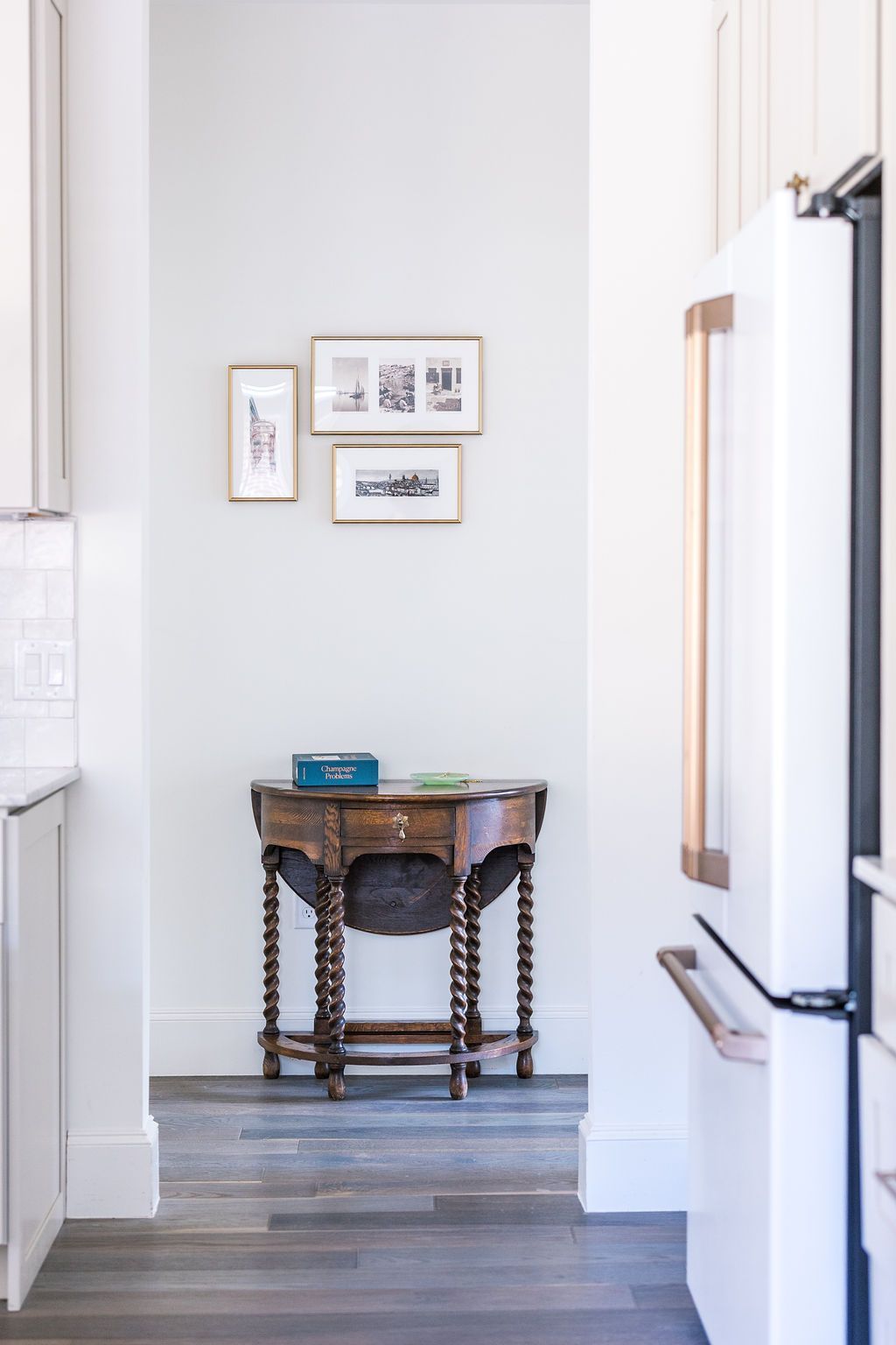 A wooden table is sitting in a hallway next to a refrigerator.