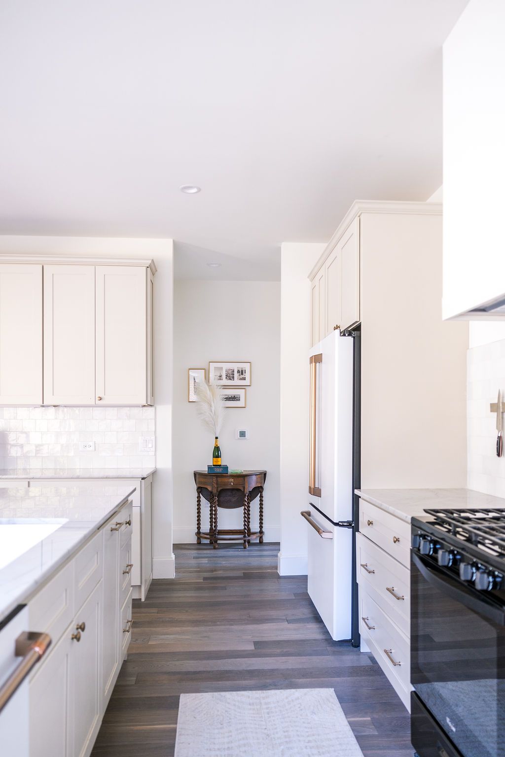 A kitchen with white cabinets , a black stove , a refrigerator , and a table.