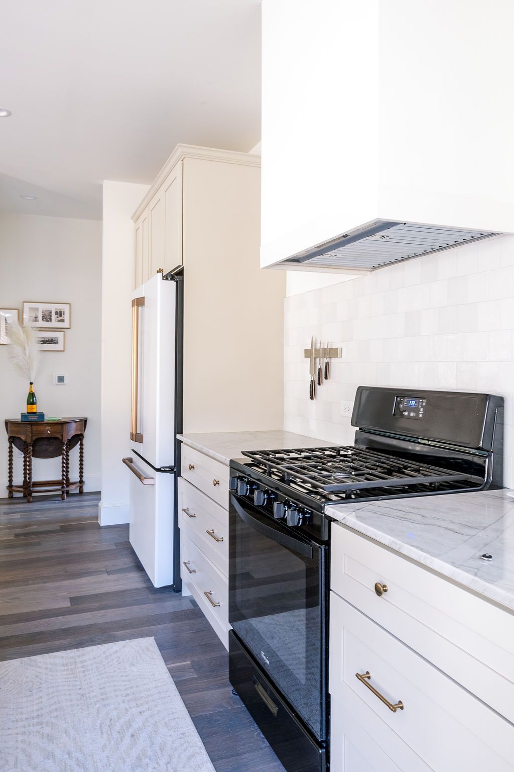 A kitchen with a stove , oven , refrigerator and white cabinets.