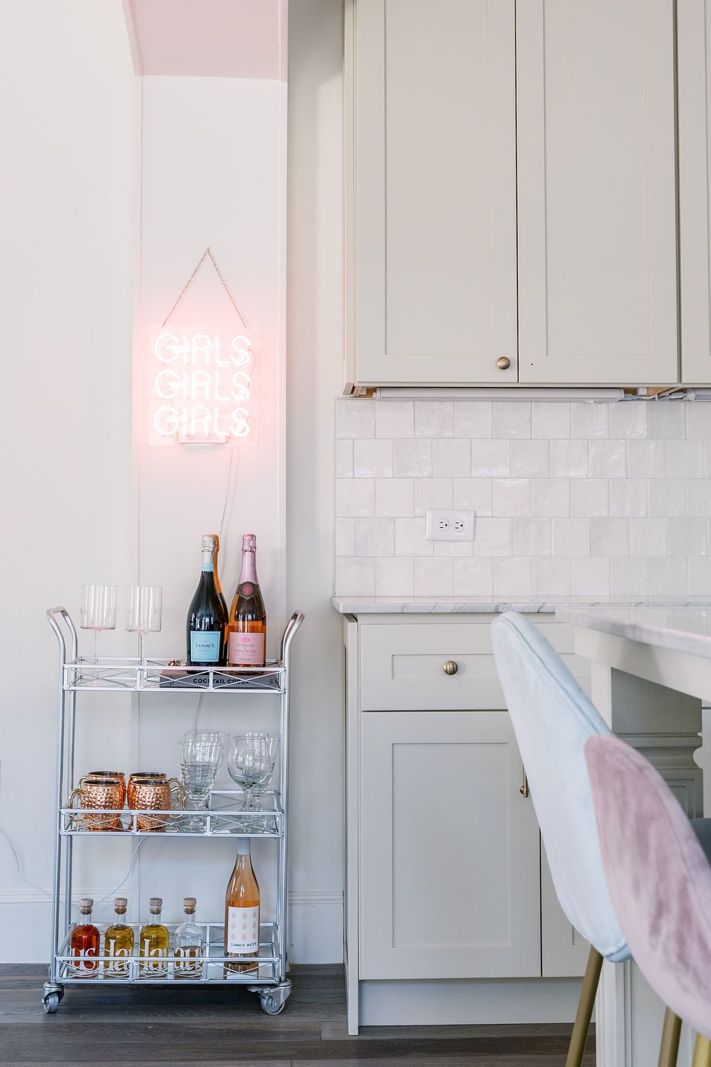 A kitchen with a bar cart and a neon sign on the wall.