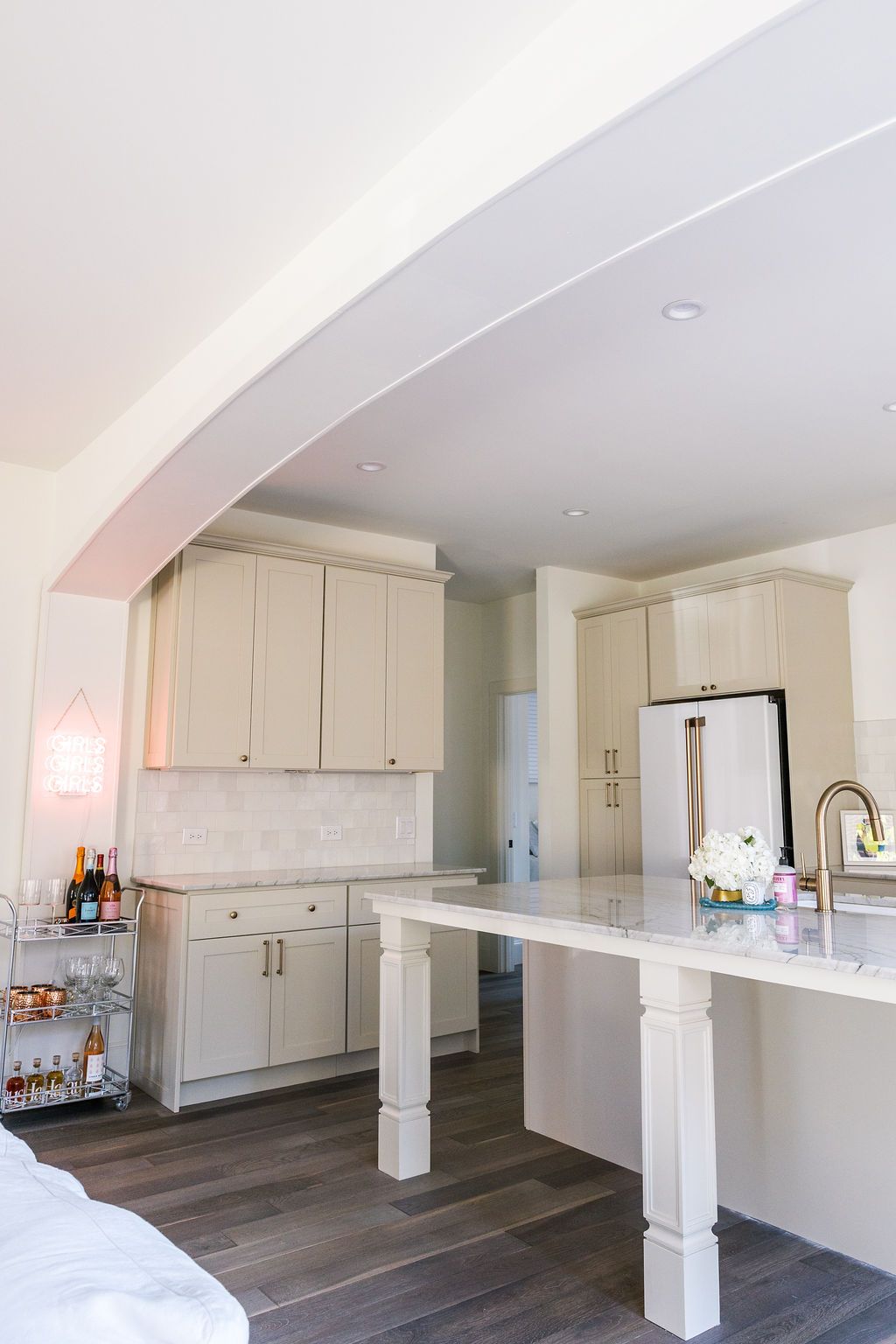 A kitchen with white cabinets , a refrigerator , a sink , and a table.