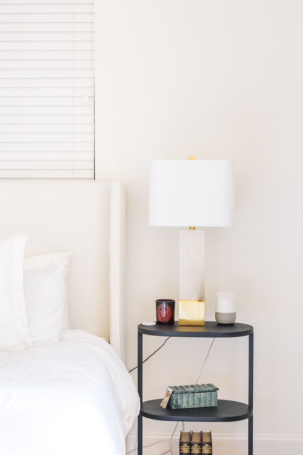 A bedroom with a bed , nightstand , lamp and window.