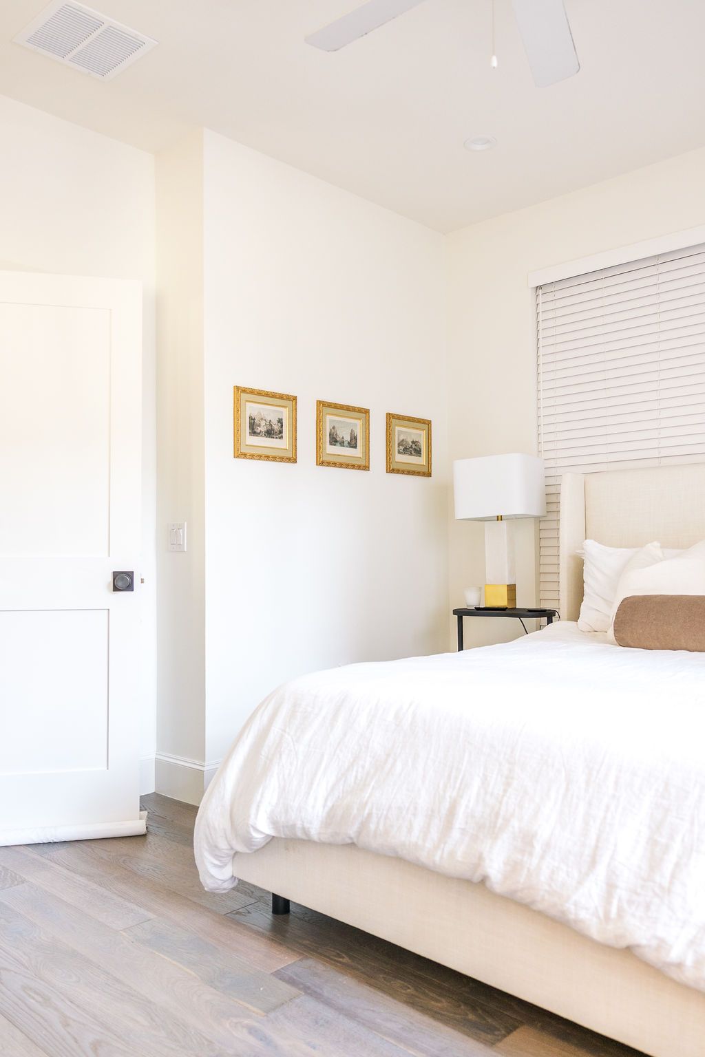 A bedroom with a bed , lamps , and pictures on the wall.