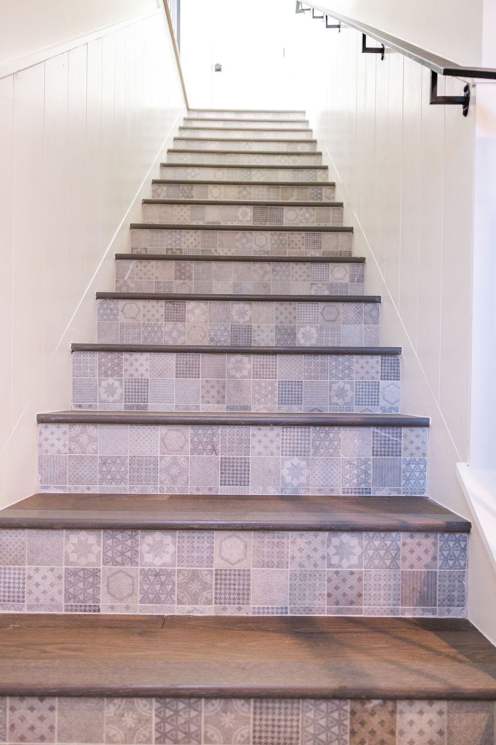 A staircase with tiles on the steps and a railing.
