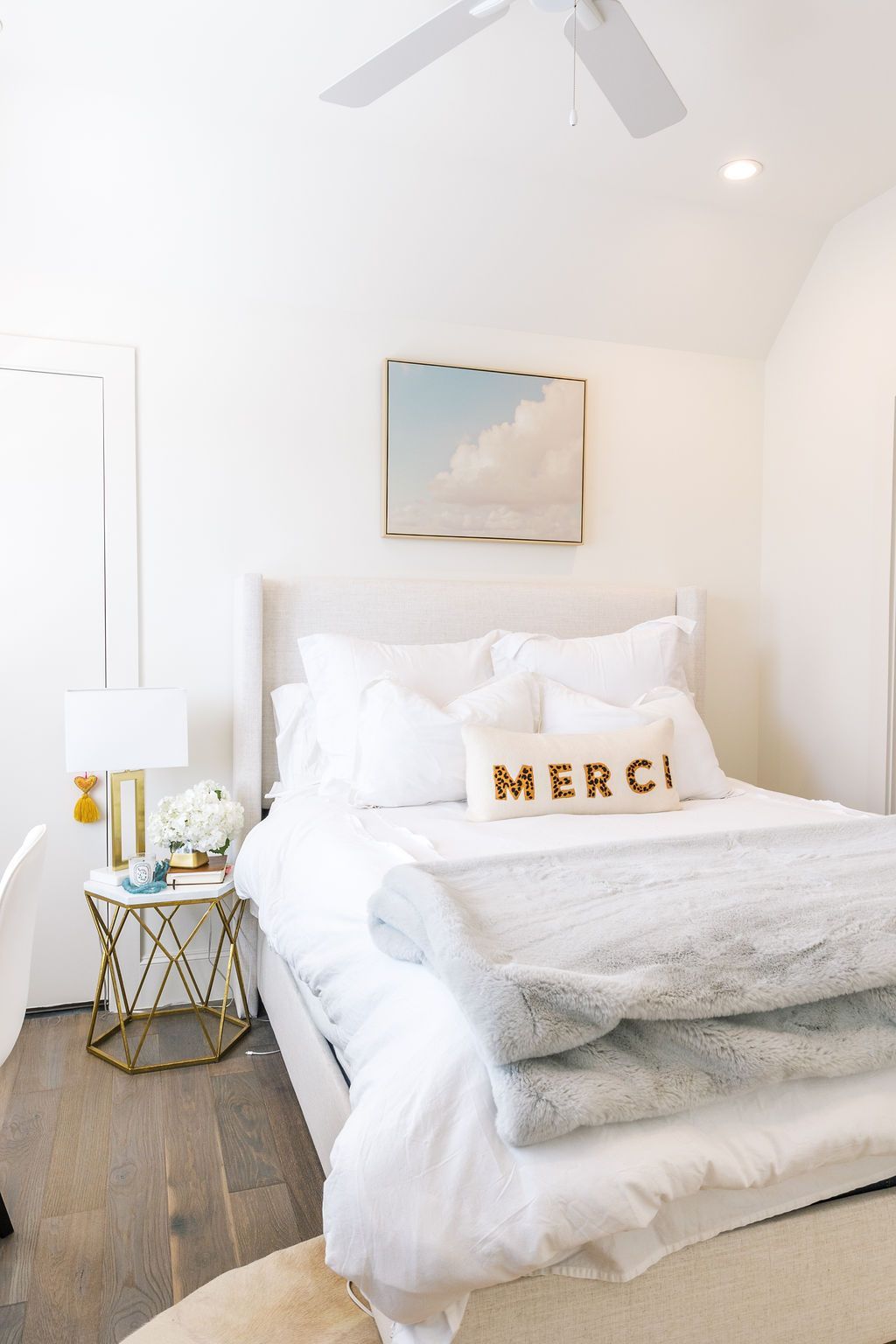 A bed with a pillow that says merci on it in a bedroom.