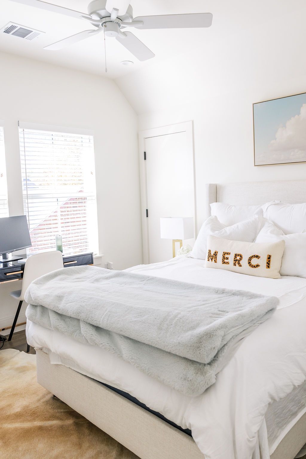 A bedroom with a bed , desk and ceiling fan.