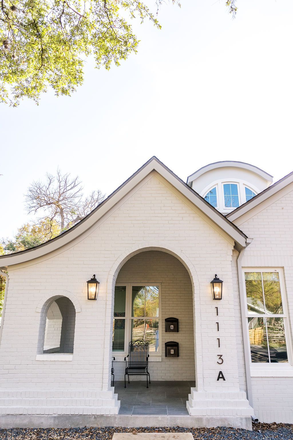 A white house with a curved roof and a porch.