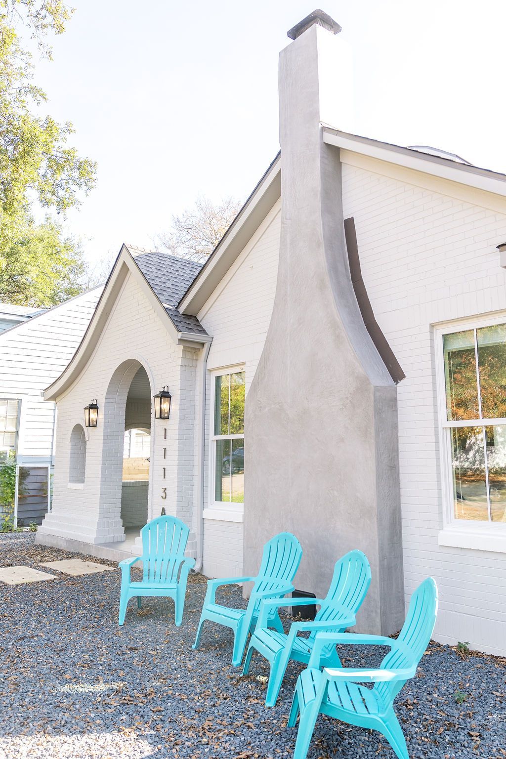 A white house with blue chairs in front of it.