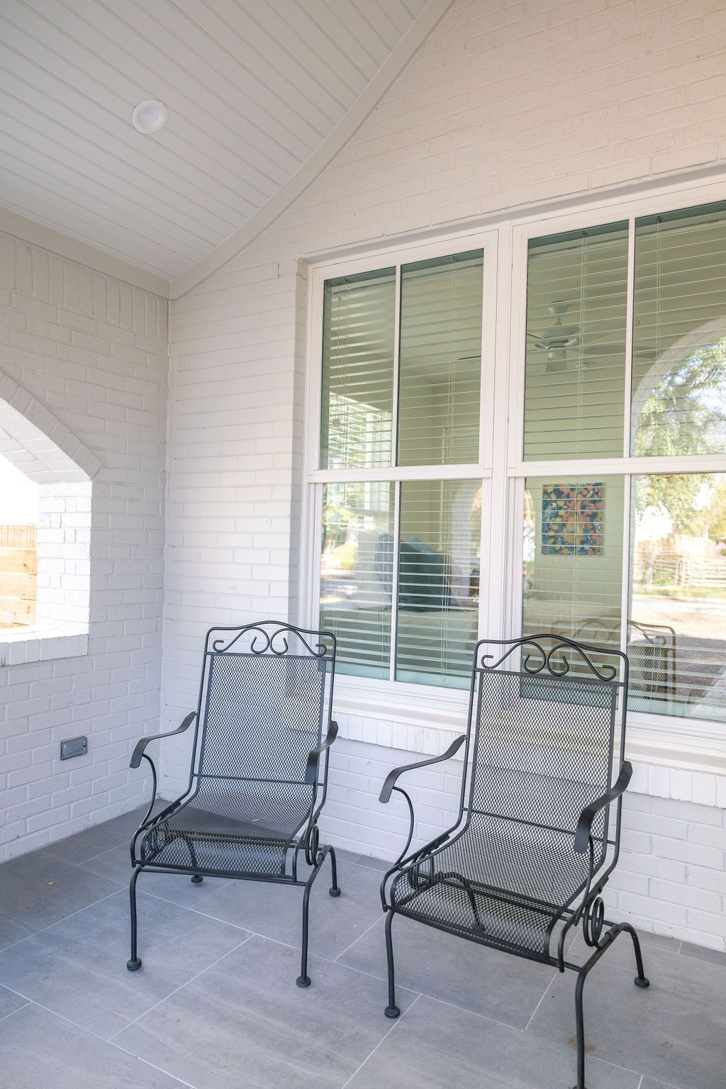 Two chairs are sitting on a porch next to a window.