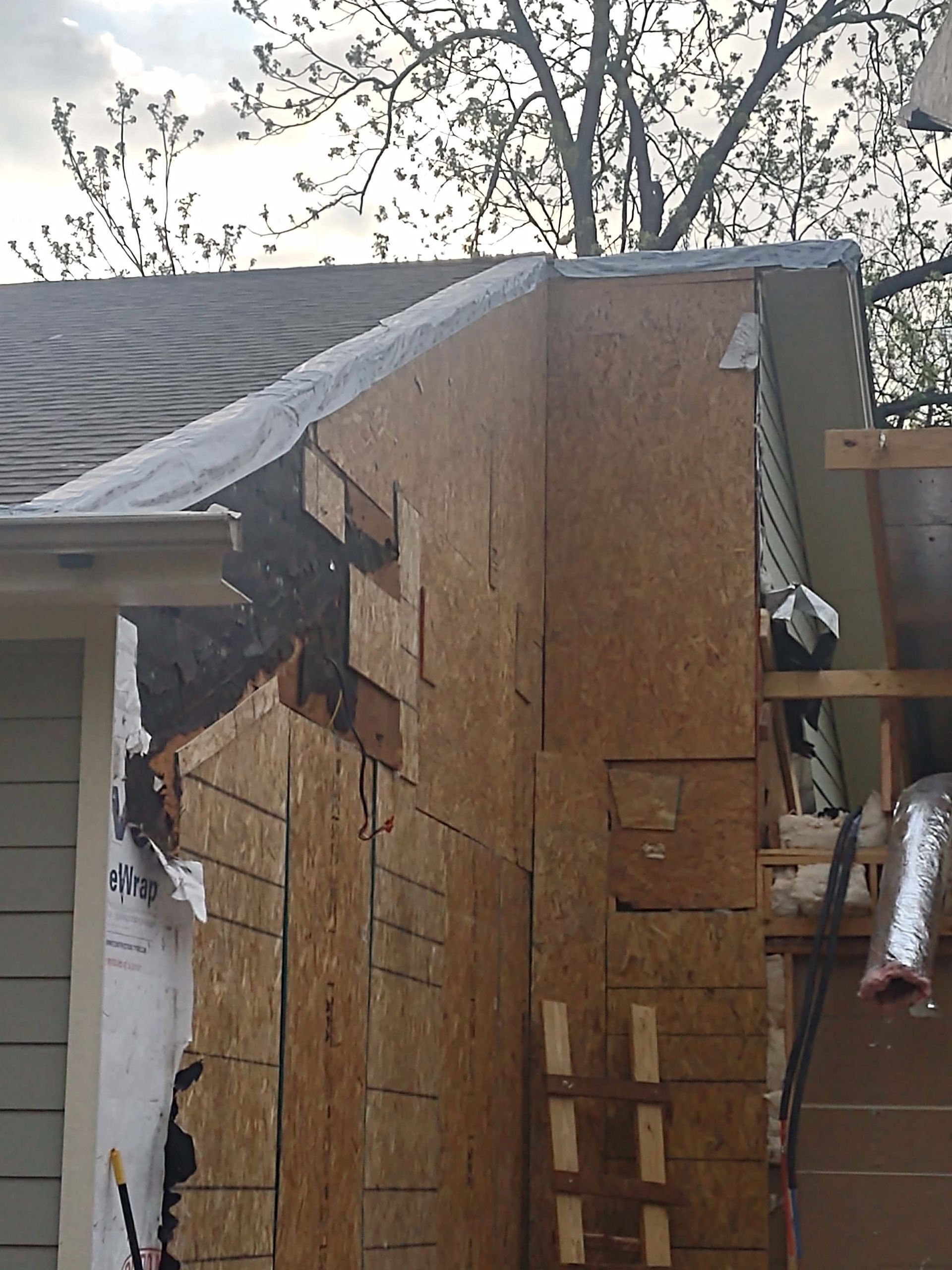 A house under construction with a tarp on the roof