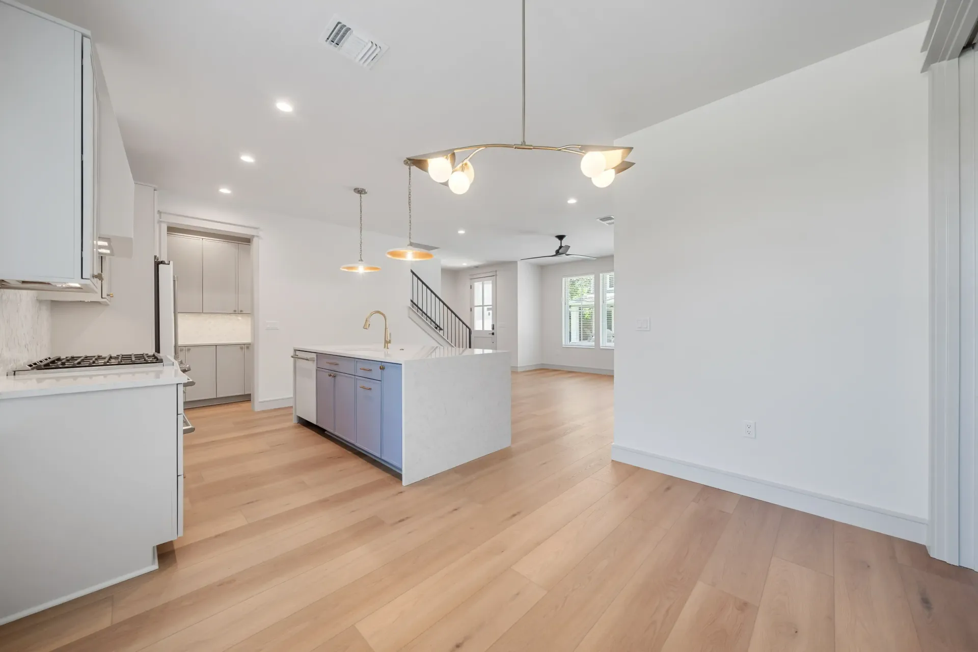 Modern kitchen with white cabinets, island, wood floors, and pendant lights.