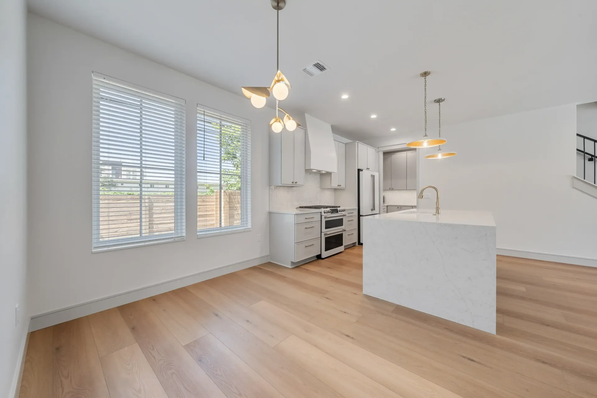 Modern kitchen with white cabinets, island, and light wood flooring.