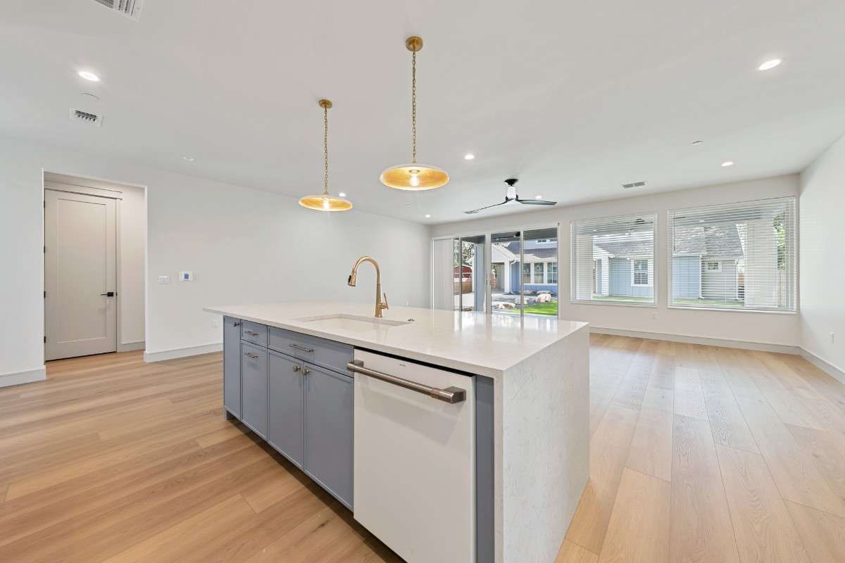 Kitchen island with light blue cabinets, white countertops, and gold pendant lights.