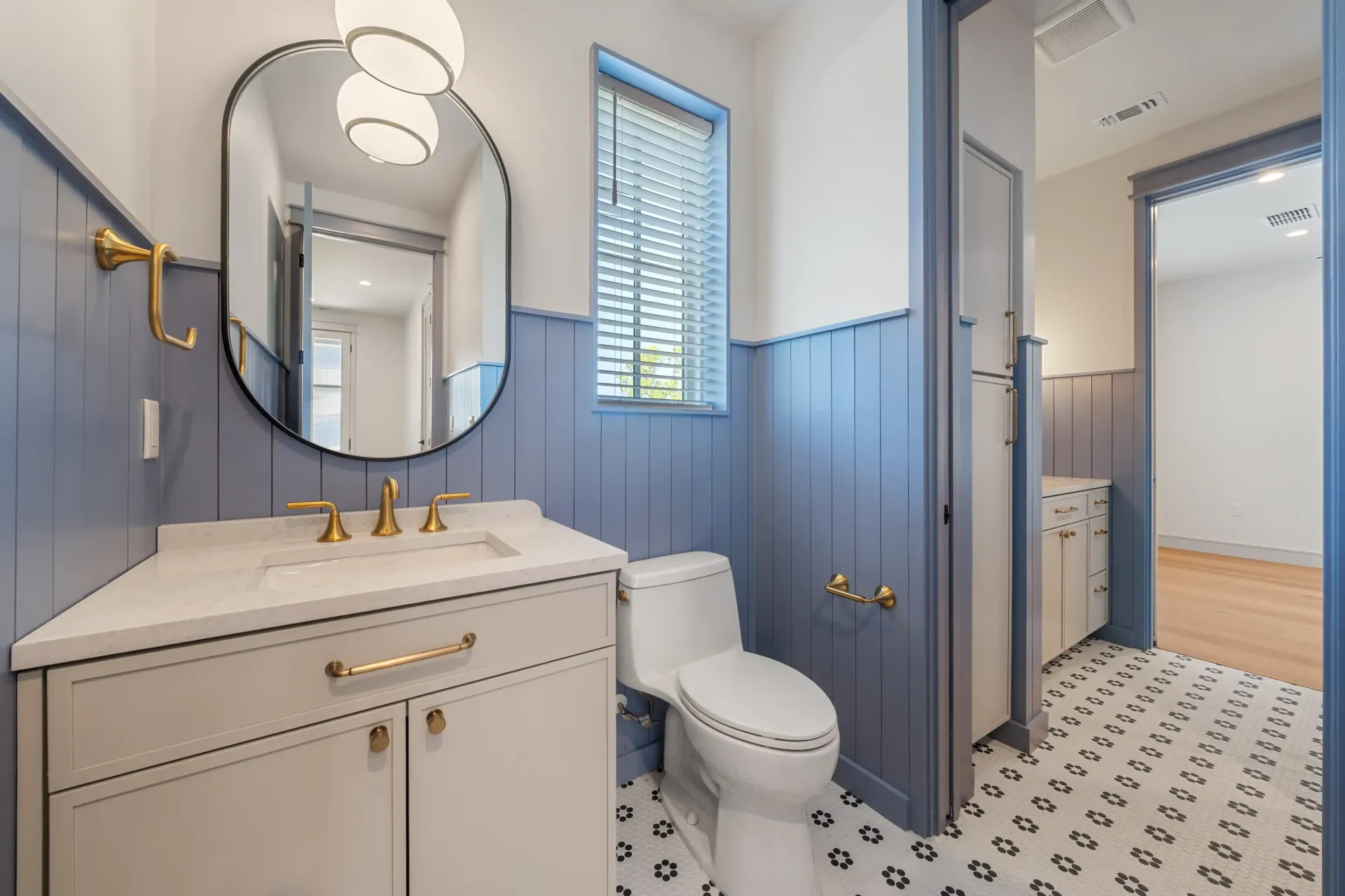 Blue and white bathroom with toilet, vanity, and patterned floor.
