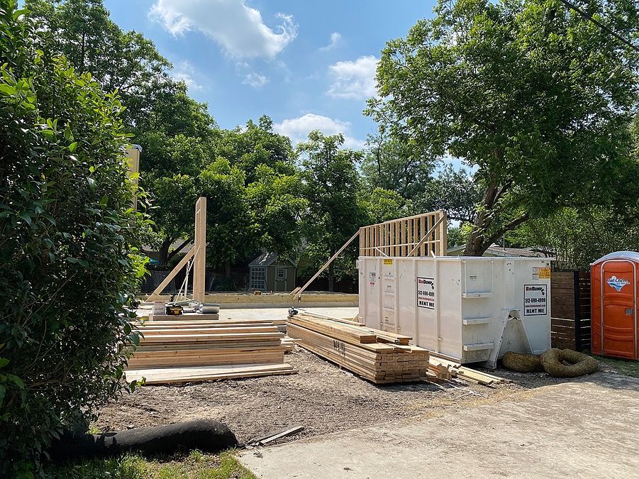 A construction site with a lot of wood and a porta potty.