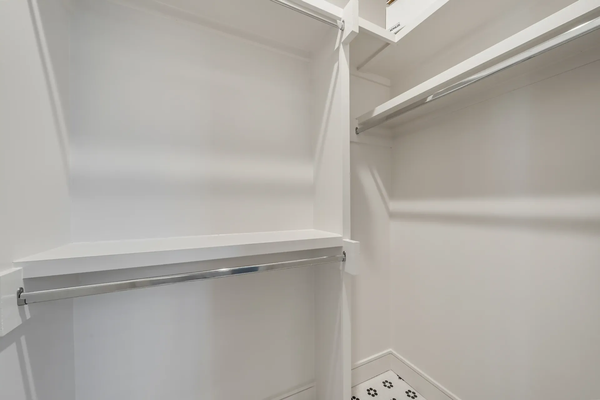 Empty white closet with shelves and a clothing rod.