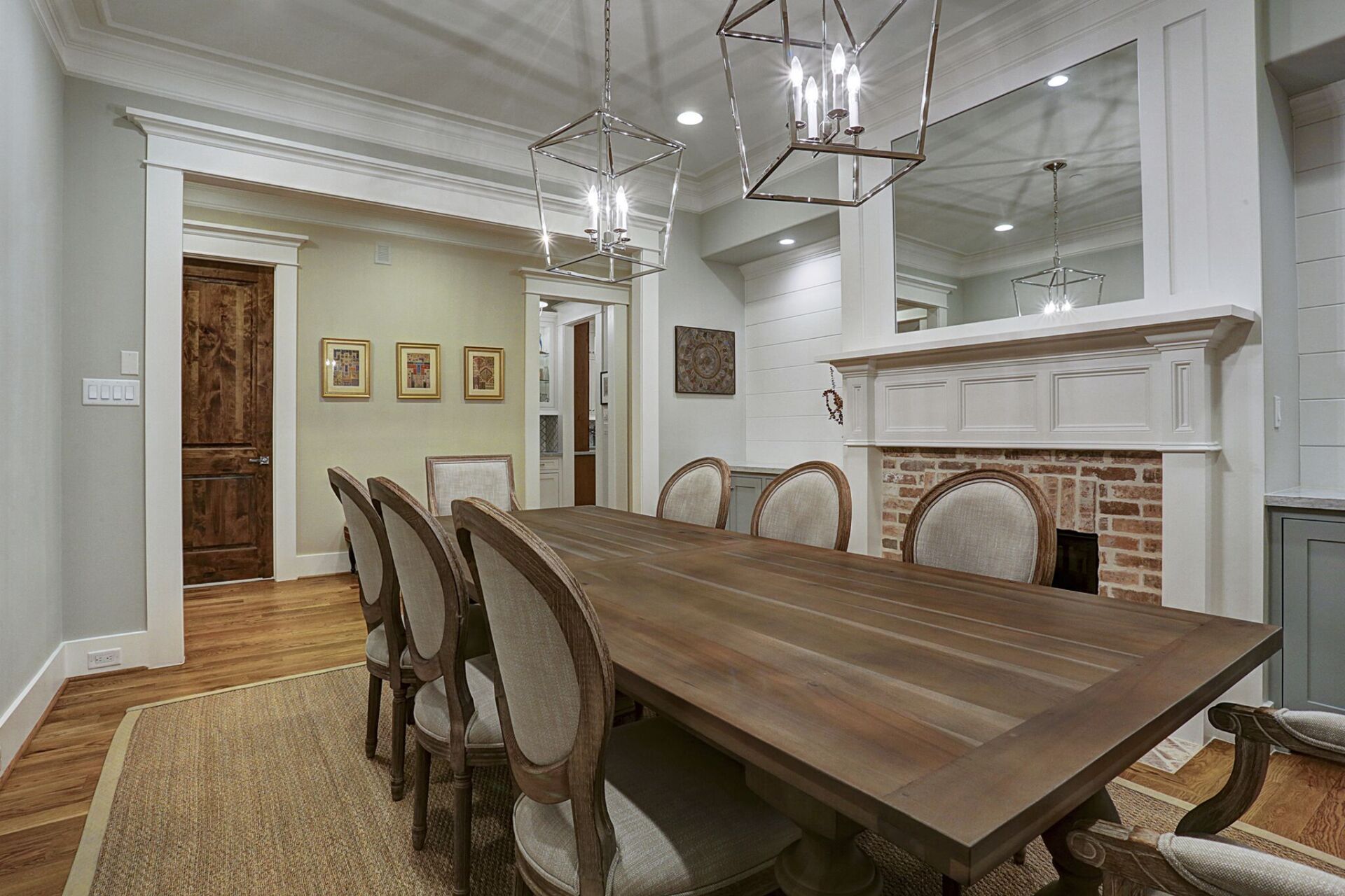 A dining room with a long wooden table and chairs and a fireplace.