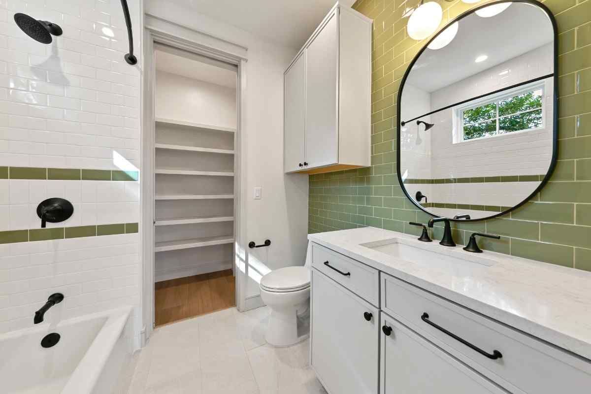 Bathroom with white vanity, green accent tiles, and storage closet.