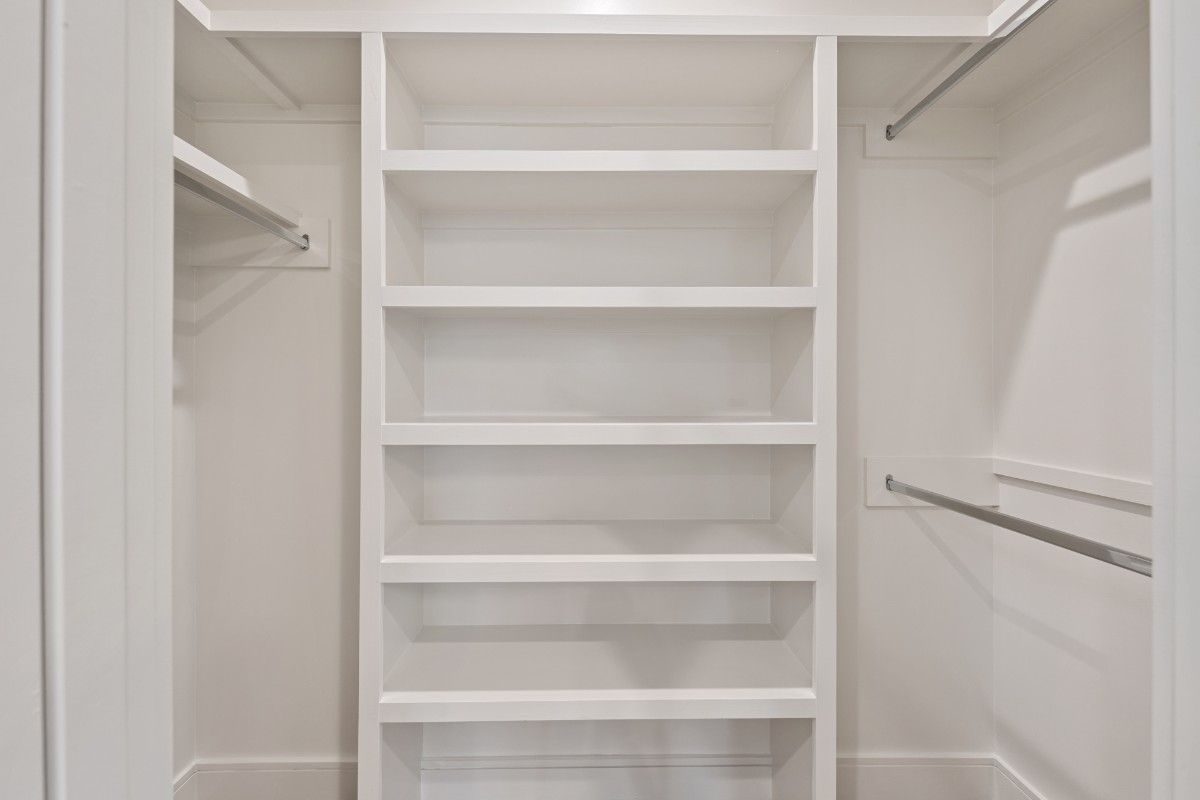 White closet interior with built-in shelves and clothing rods.