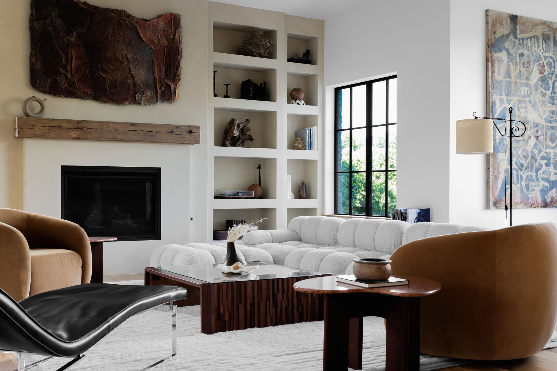 Living room with white sofa, fireplace, built-in shelves, modern furniture, and large art.